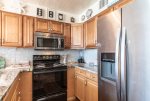 kitchen with upgraded cabinets, stainless steel microwave and refrigerator, oven-range, blender, beach art